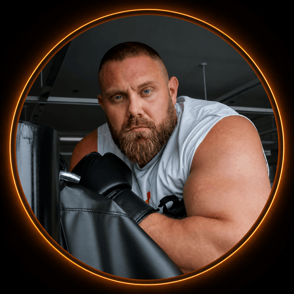 Bearded man in a white sleeveless shirt leans on a boxing bag, wearing black gloves, inside a gym with a circular neon frame around him.